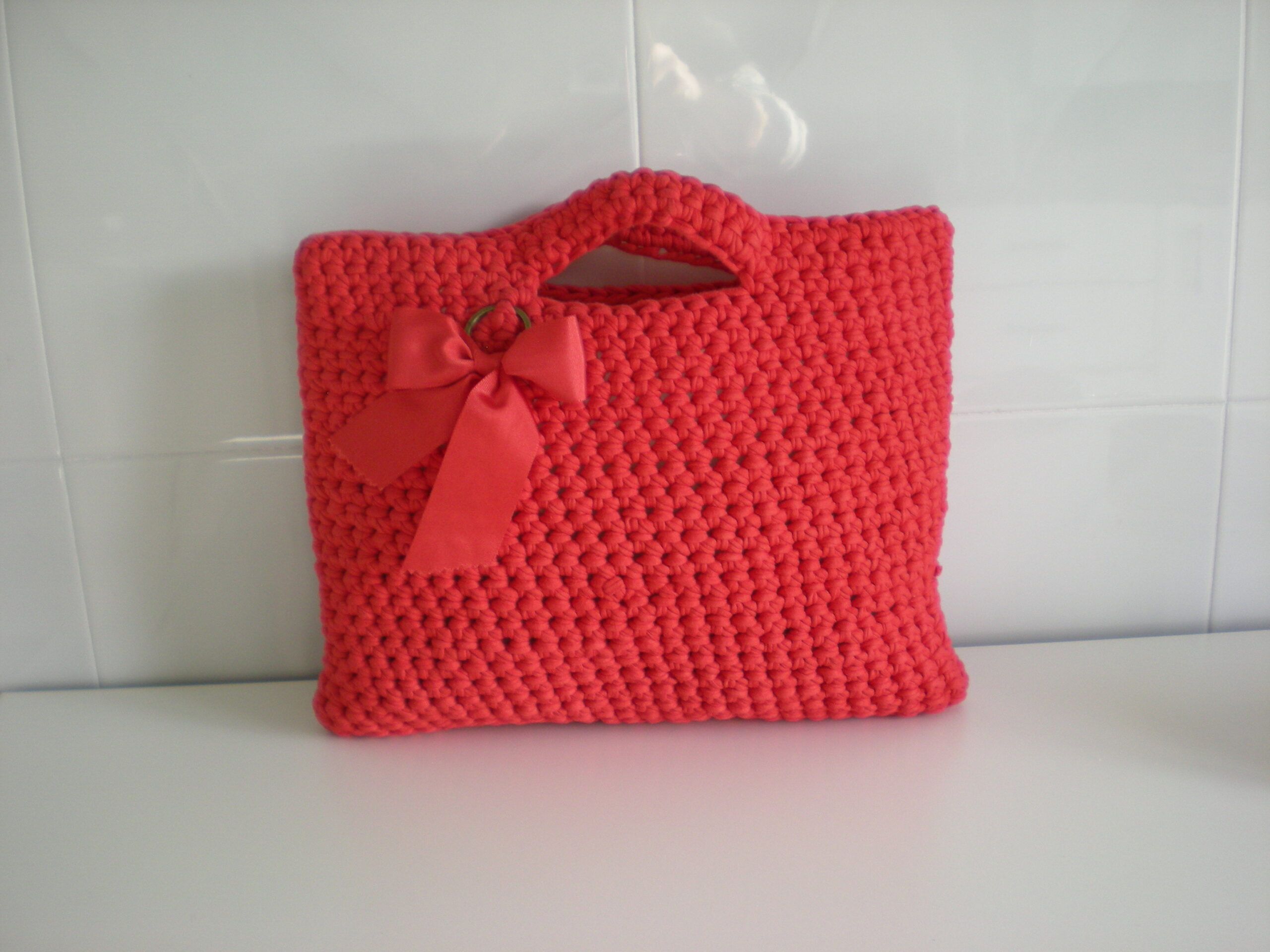 Bolso hecho a mano tricotando de color rojo y adorno con lazada